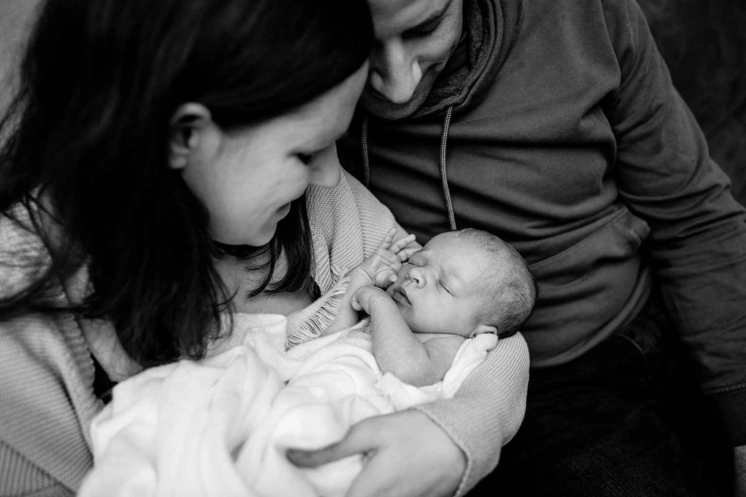 Mama, Papa und schlafendes Baby im Arm in schwarz weiß