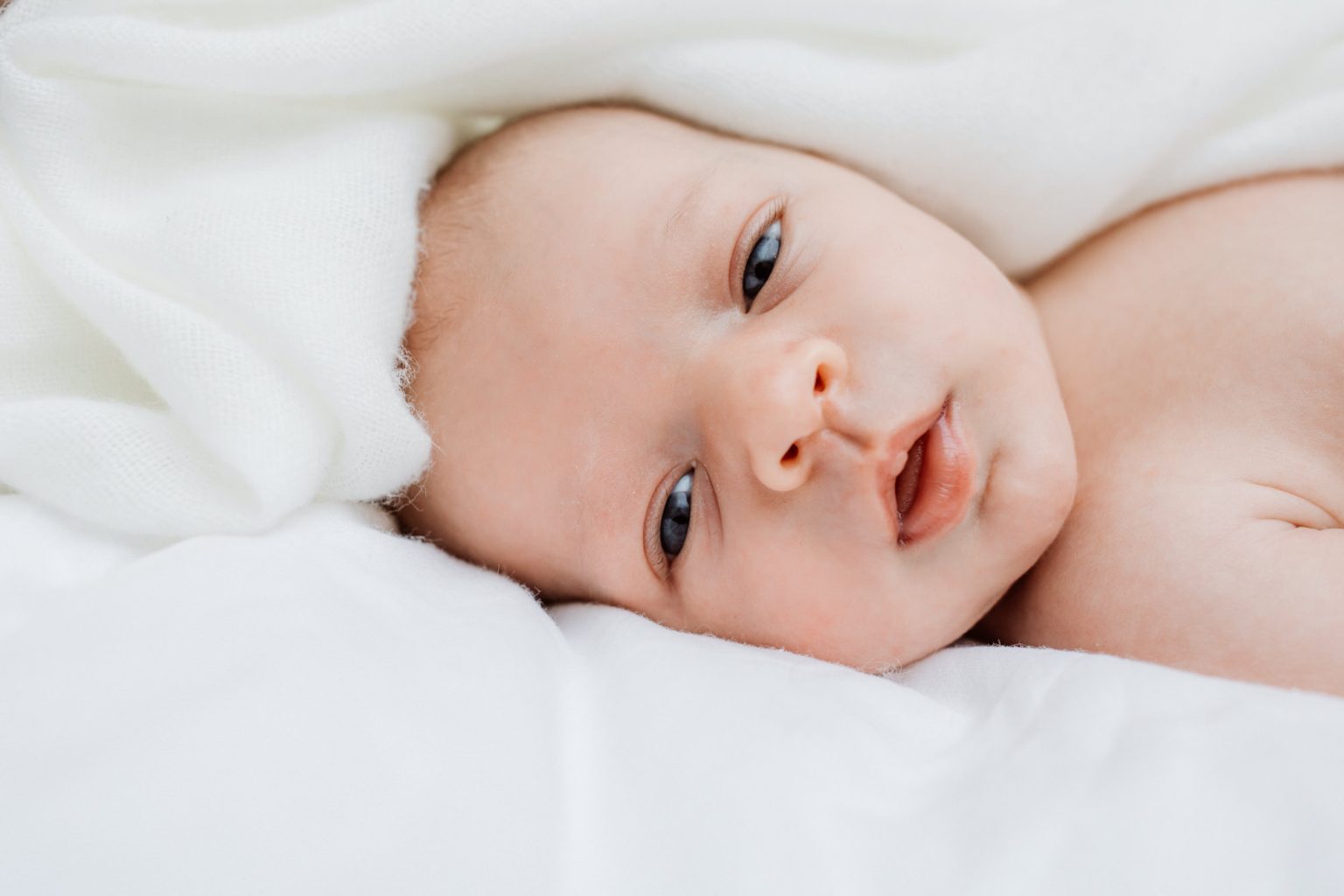 Baby kuschelt beim Fotoshooting unter der Decke Fotos zu Hause Fotograf