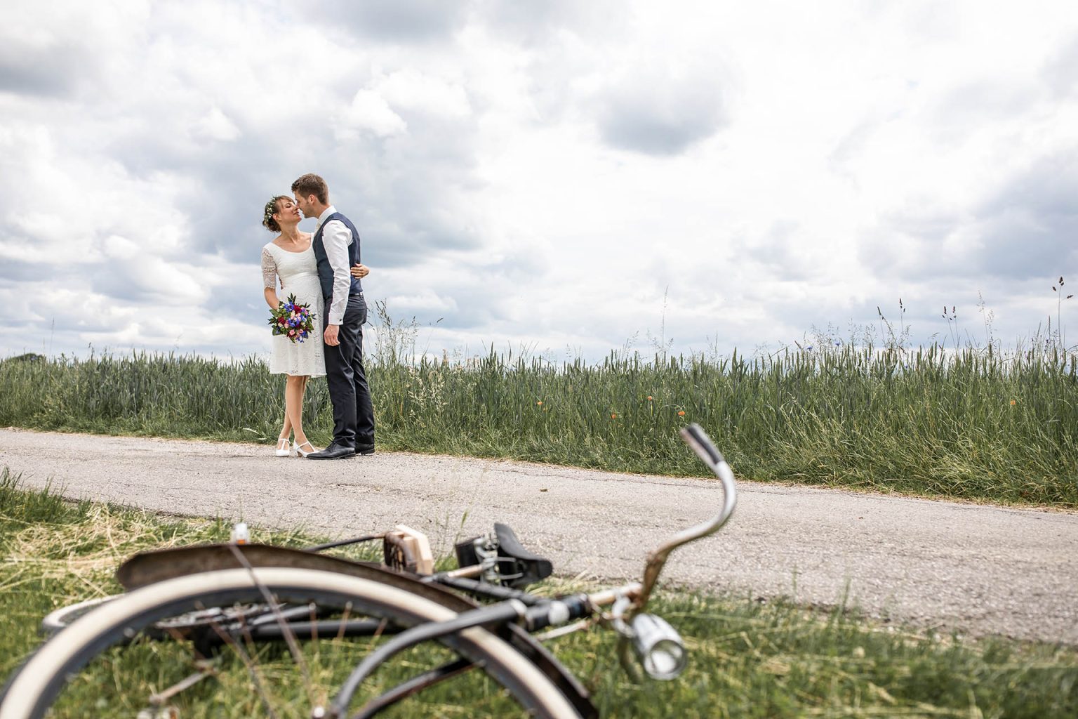 Hochzeitsfotos mit altem Fahrrad im Vordergrund in der Natur