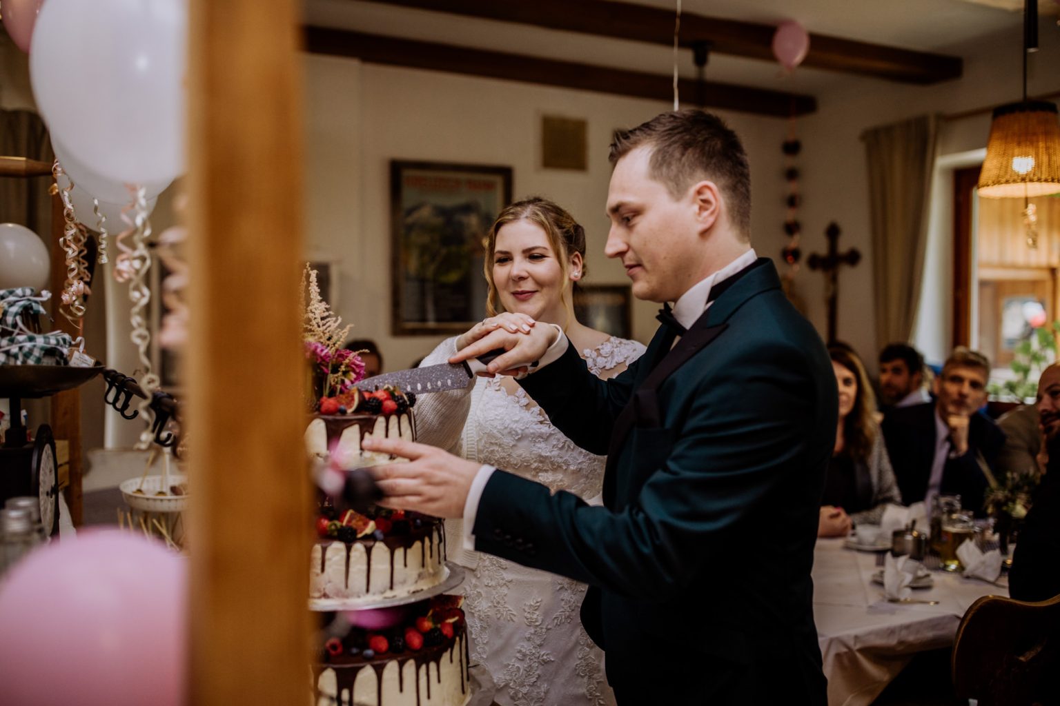 Braut und Bräutigam schneiden zusammen die Hochzeitstorte auf der Tonihütte an