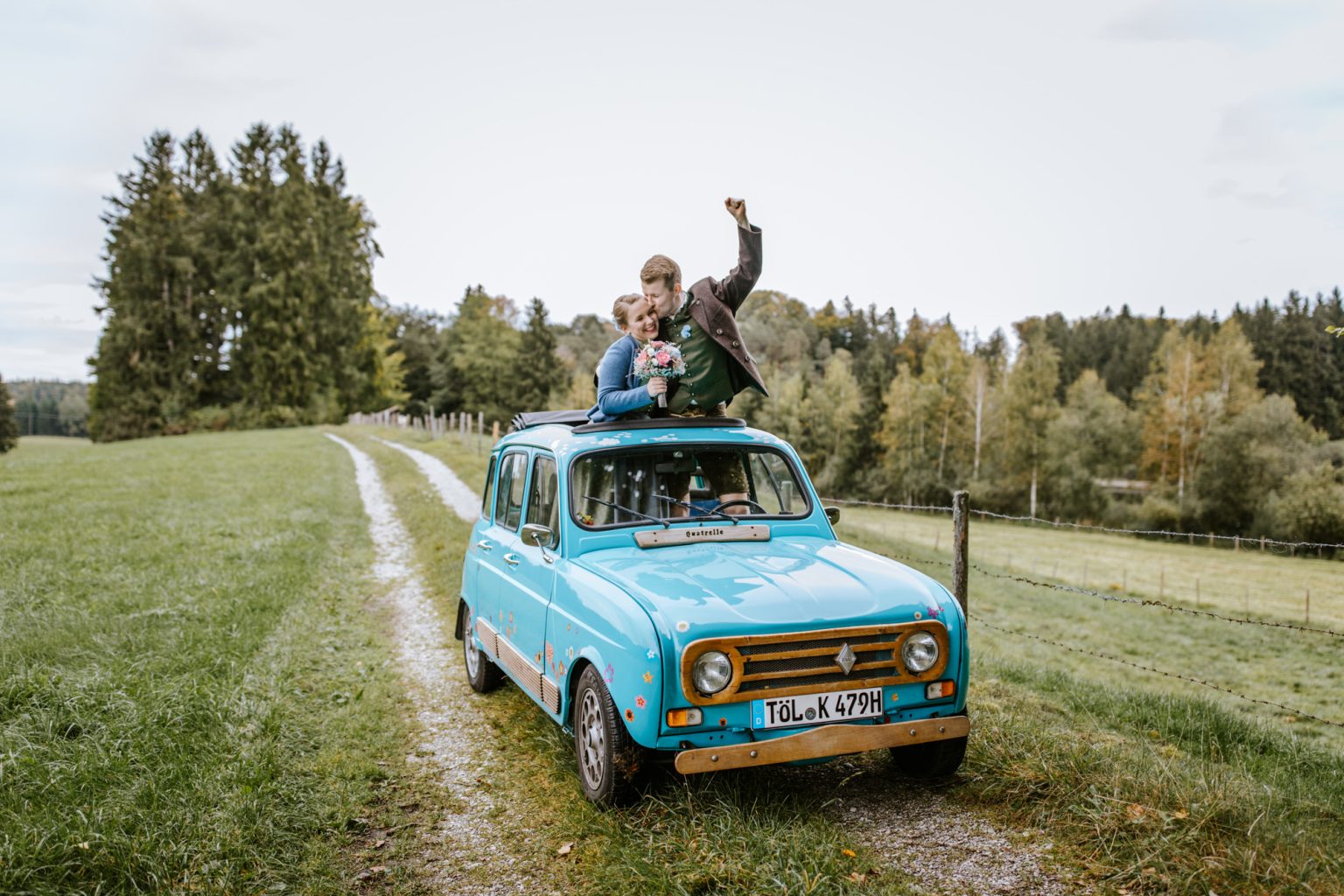 Braut und Bräutigam schauen oben aus ihrem Hochzeitsauto raus