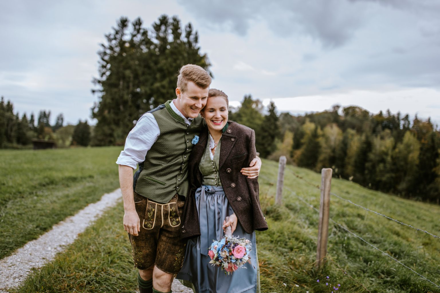 Braut in der Trachtenjacke von ihrem Bräutigam