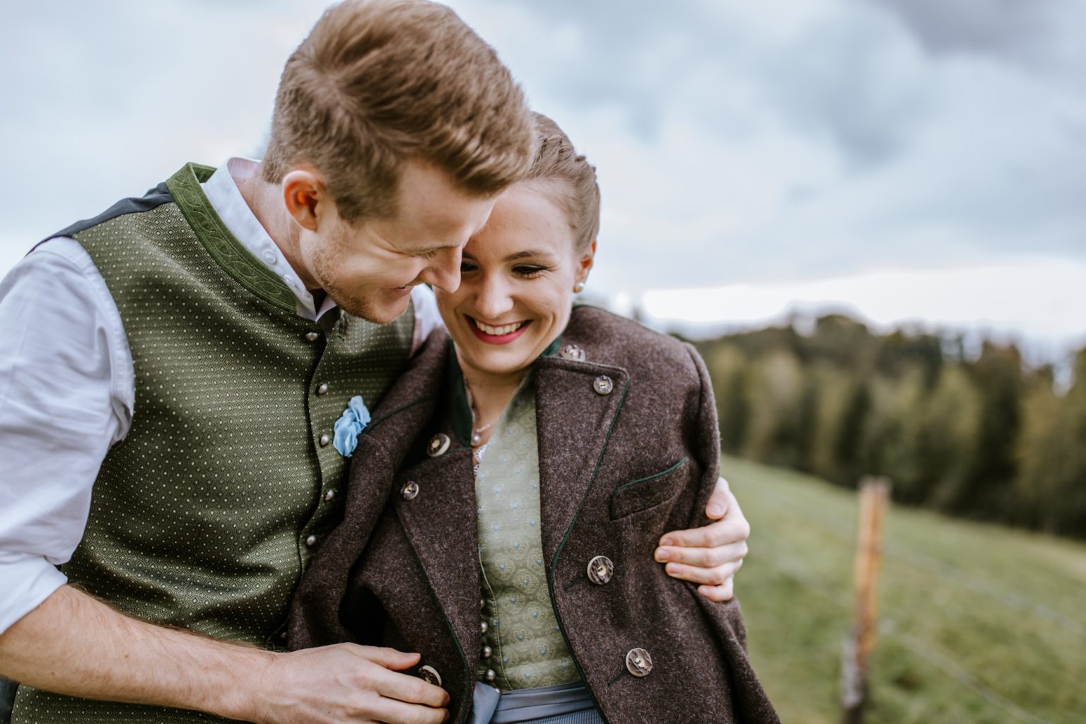 Bräutigam in Lederhose wärmt seine Frau im Dirndl