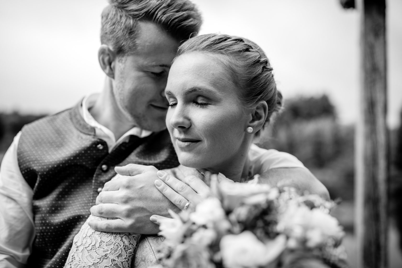 Bräutigam lehnt seinen Kopf an die Schulter seiner zukünftigen Frau in Tracht bei Weilheim