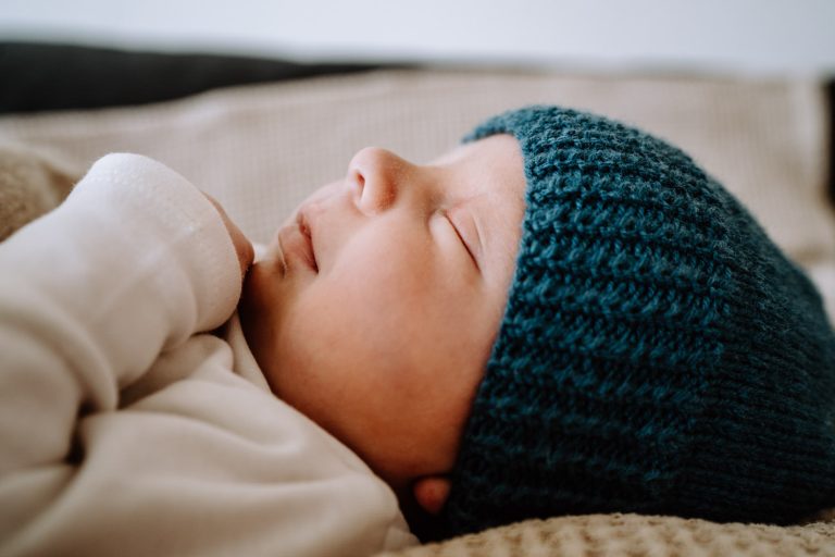 Baby schlaft auf dem Sofa bei Neugeborenenfotos daheim