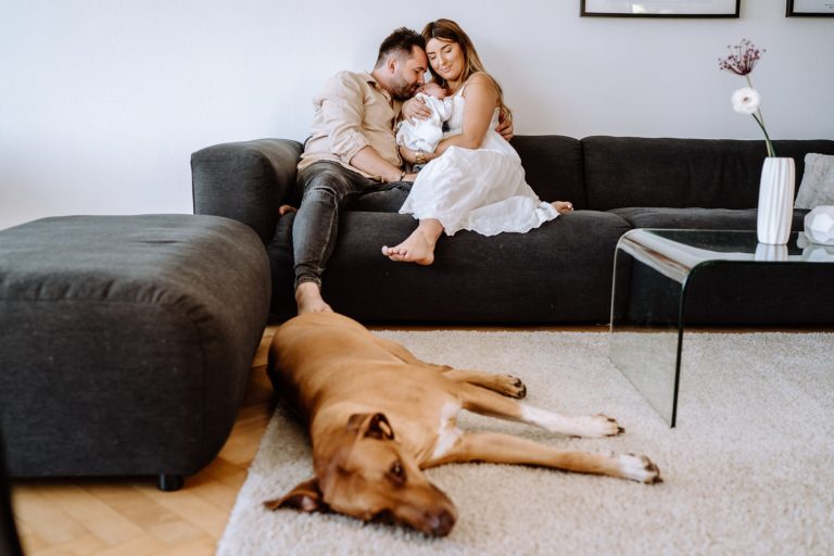 Babyfotos als Homestory zu Hause, zusammen mit dem Hund vor dem Sofa