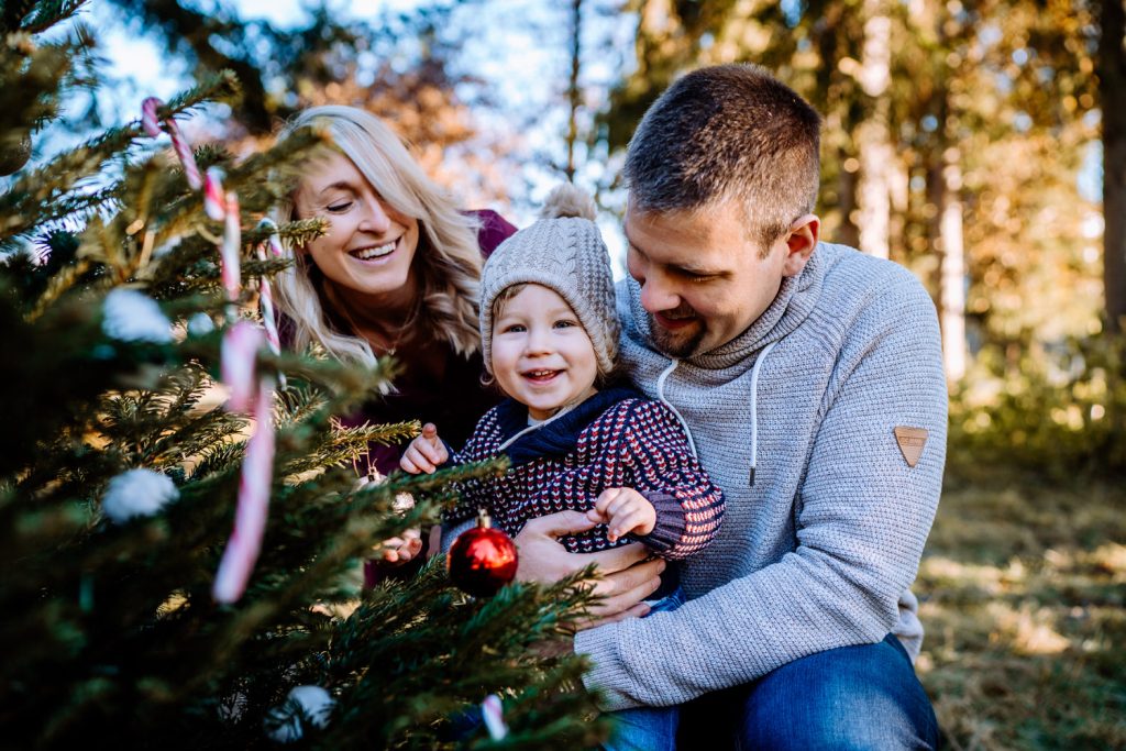Weihnachtsshootings in Weilheim - Familie sitzt am geschmückten Weihnachtsbaum in der Natur