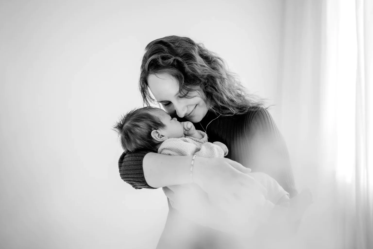 Liebevolle schwarz weiß Babyfotos im Fotostudio in Weilheim - Mama hält ihr Baby in dem Arm