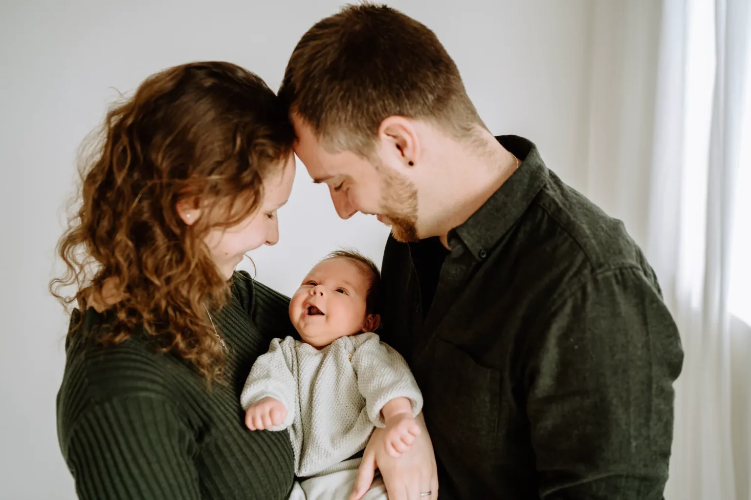 Glückliche Familie - Mama und Papa mit dem Baby auf dem Arm