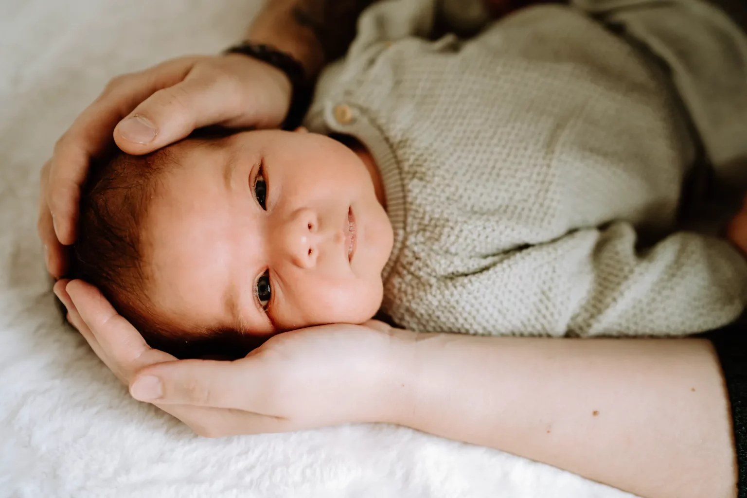 Außergewöhnliche Babyfotos - Mama hält den Kopf von ihrem Neugeborenen in den Händen